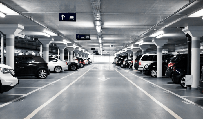 A monochrome image of a parking garage, showcasing its structure and vehicles parked inside.