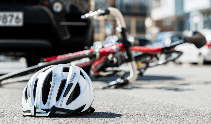 A bicycle helmet rests on the ground near a car, emphasizing the importance of safety for cyclists.