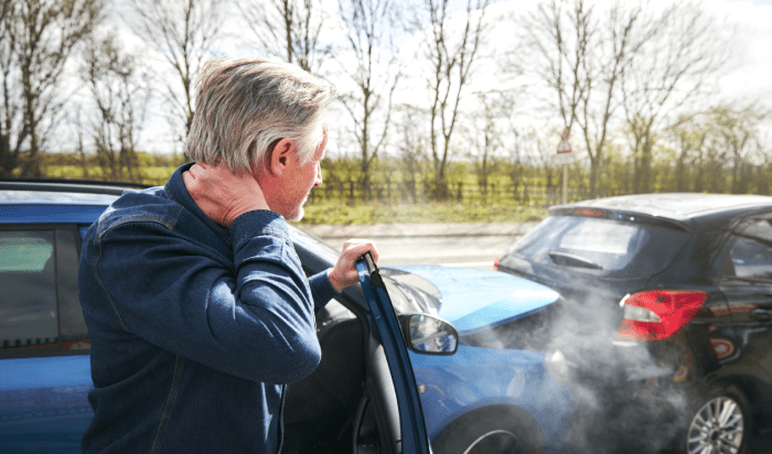 A man inspecting his damaged car after an accident.