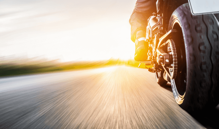 A blurred motorcycle speeding on the road, creating a sense of motion.