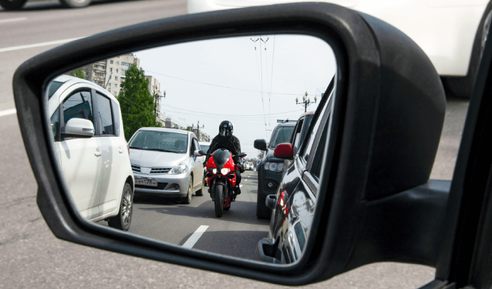 Side view mirror of a car reflecting a motorcycle parked beside it.