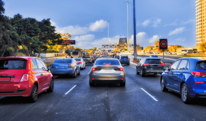 Cars driving on a busy road with traffic lights.