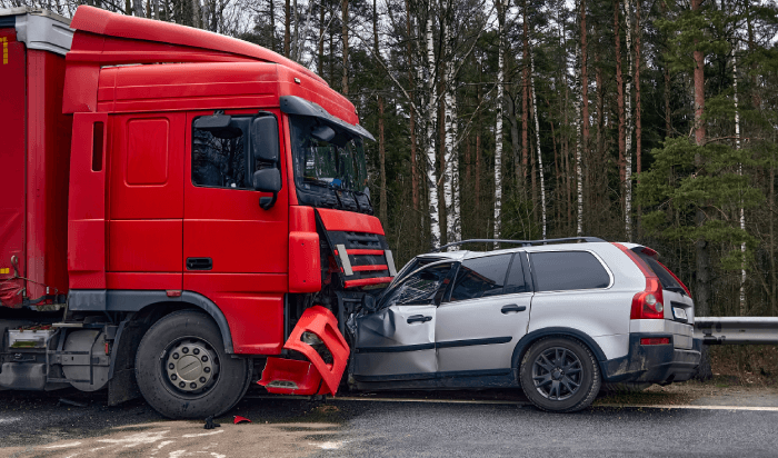 A red truck and a white car collide on the road, resulting in a crash.
