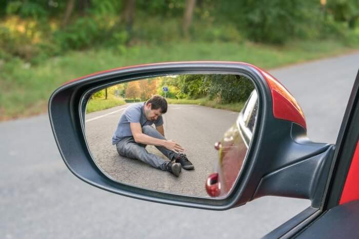 Hit and run concept Hit and run concept. View on injured man on road in rear mirror of a car.